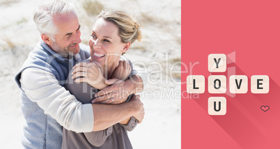 Composite image of happy hugging couple on the beach looking at