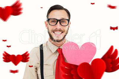 Composite image of geeky hipster smiling and holding heart card