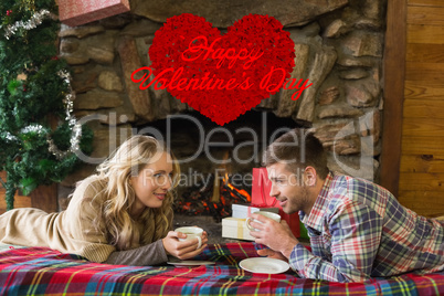 Composite image of couple with tea cups in front of lit fireplac