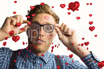 Composite image of geeky hipster covered in kisses