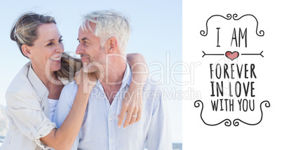 Composite image of attractive married couple hugging at the beac