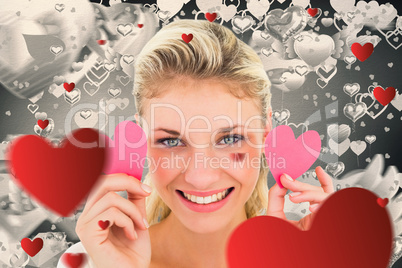 Composite image of attractive young blonde holding little hearts
