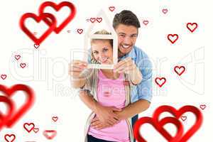 Composite image of young couple hugging and holding house outlin