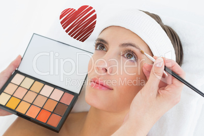 Composite image of hand applying eyeshadow to beautiful woman