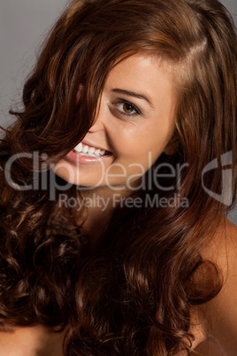 young woman portrait with shiny healthy brown curly hair