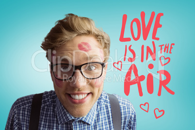 Composite image of geeky hipster covered in kisses