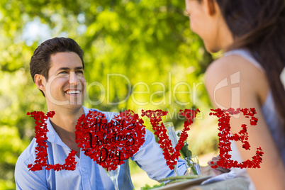 Composite image of couple with champagne flutes sitting at an ou