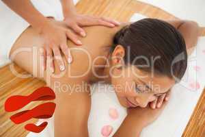 Composite image of beautiful brunette enjoying a back massage