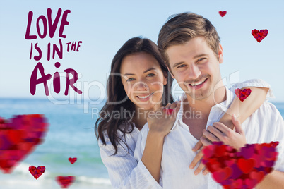 Composite image of cheerful couple embracing on the beach