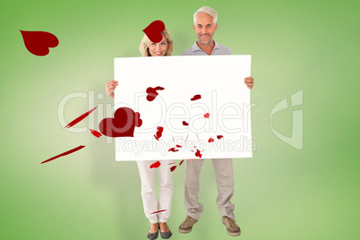 Composite image of happy couple holding large poster