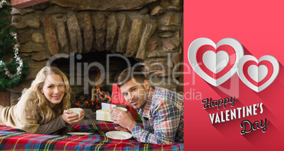 Composite image of couple with tea cups in front of lit fireplac