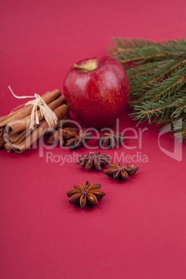 christmas decoration red apple, cinnamon, anise and tree on red background