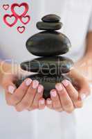 Composite image of beauty therapist holding pile of stones for m
