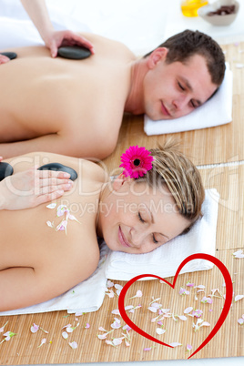 Composite image of young couple enjoying a back massage with sto