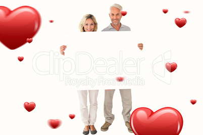 Composite image of happy couple holding large poster