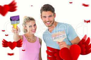 Composite image of young couple smiling and holding paintbrushes