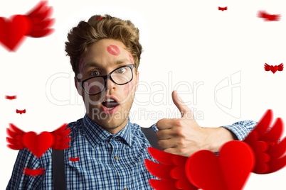 Composite image of geeky hipster covered in kisses