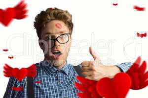 Composite image of geeky hipster covered in kisses