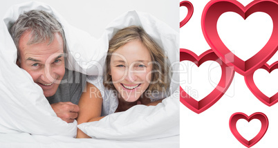 Composite image of happy middle aged couple under the duvet Composite image of happy middle aged couple under the duvet