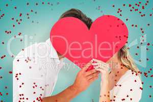 Composite image of attractive young couple kissing behind large