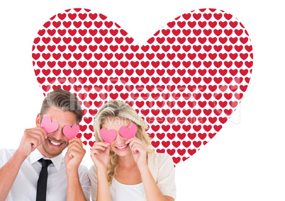 Composite image of attractive young couple holding pink hearts o