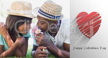 Composite image of happy couple lying in garden together smellin