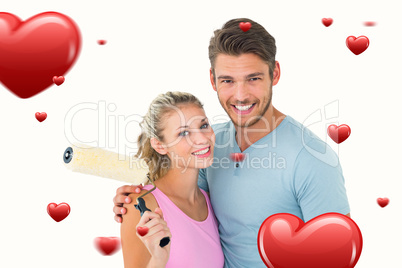 Composite image of young couple hugging and holding paint roller Composite image of young couple hugging and holding paint roller