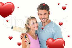 Composite image of young couple hugging and holding paint roller
