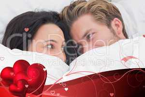 Composite image of couple under the duvet looking at each other