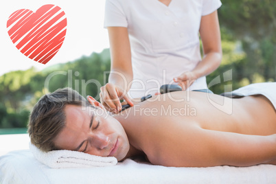 Composite image of handsome man getting a hot stone massage pool