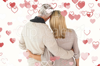 Composite image of happy couple standing with arms around