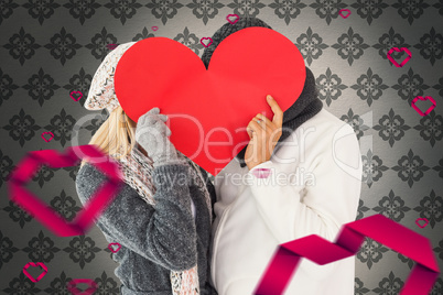 Composite image of couple in winter fashion posing with heart sh