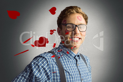 Composite image of geeky hipster covered in kisses