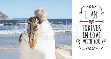 Composite image of couple wrapped up in blanket on the beach loo
