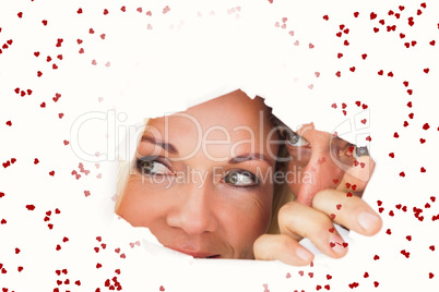 Composite image of couple looking through torn paper