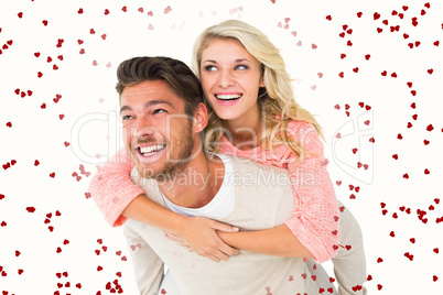 Composite image of handsome man giving piggy back to his girlfri