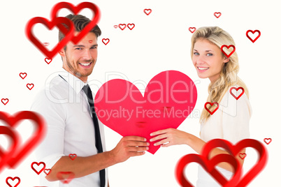 Composite image of attractive young couple holding red heart