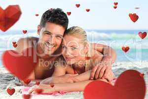 Composite image of lovers lying down on the beach