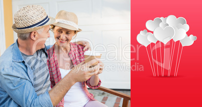 Composite image of happy mature couple drinking coffee on a benc