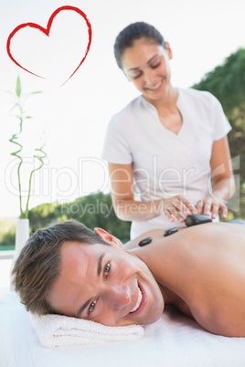 Composite image of handsome man getting a hot stone massage pool