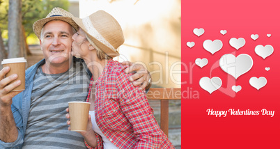 Composite image of happy mature couple drinking coffee on a benc