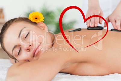 Composite image of delighted woman having a hot stone massage