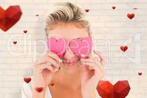 Composite image of attractive young blonde holding hearts over e
