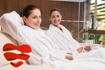 Composite image of smiling women in bathrobes sitting on couch