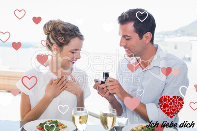 Composite image of man surprising woman with a wedding ring at l