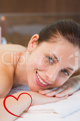 Composite image of beautiful woman lying on massage table at spa