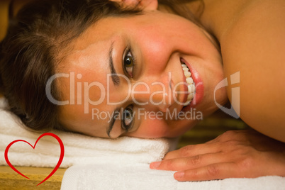 Composite image of happy brunette lying in a sauna looking at ca