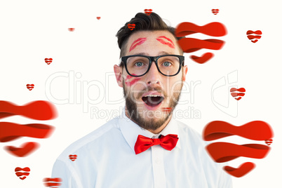 Composite image of geeky hipster with kisses on his face