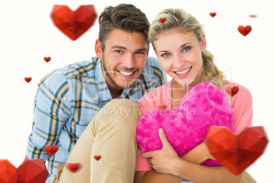 Composite image of attractive young couple sitting holding heart