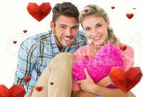 Composite image of attractive young couple sitting holding heart